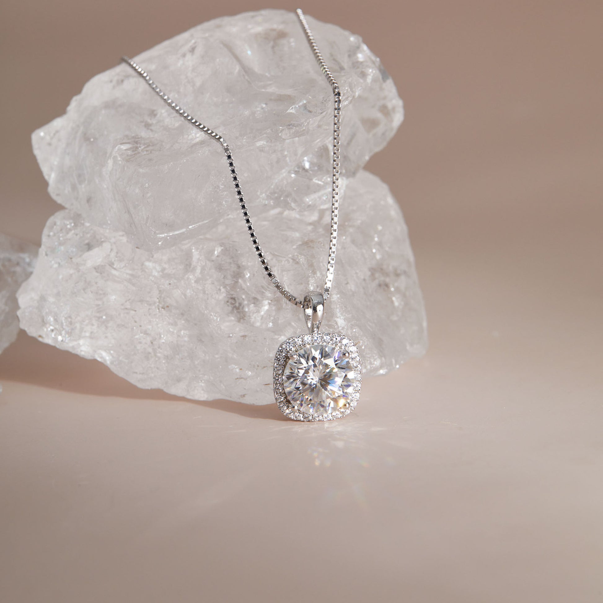 Close-up of moissanite cushion halo pendant showing round center stone and square setting against crystal