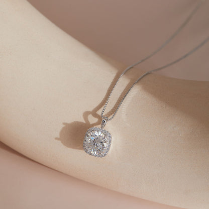 Sterling silver moissanite square halo pendant hanging against soft fabric, close-up