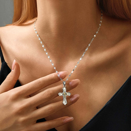 Woman wearing oxidized sterling silver cross pendant necklace, close-up on neck and chain