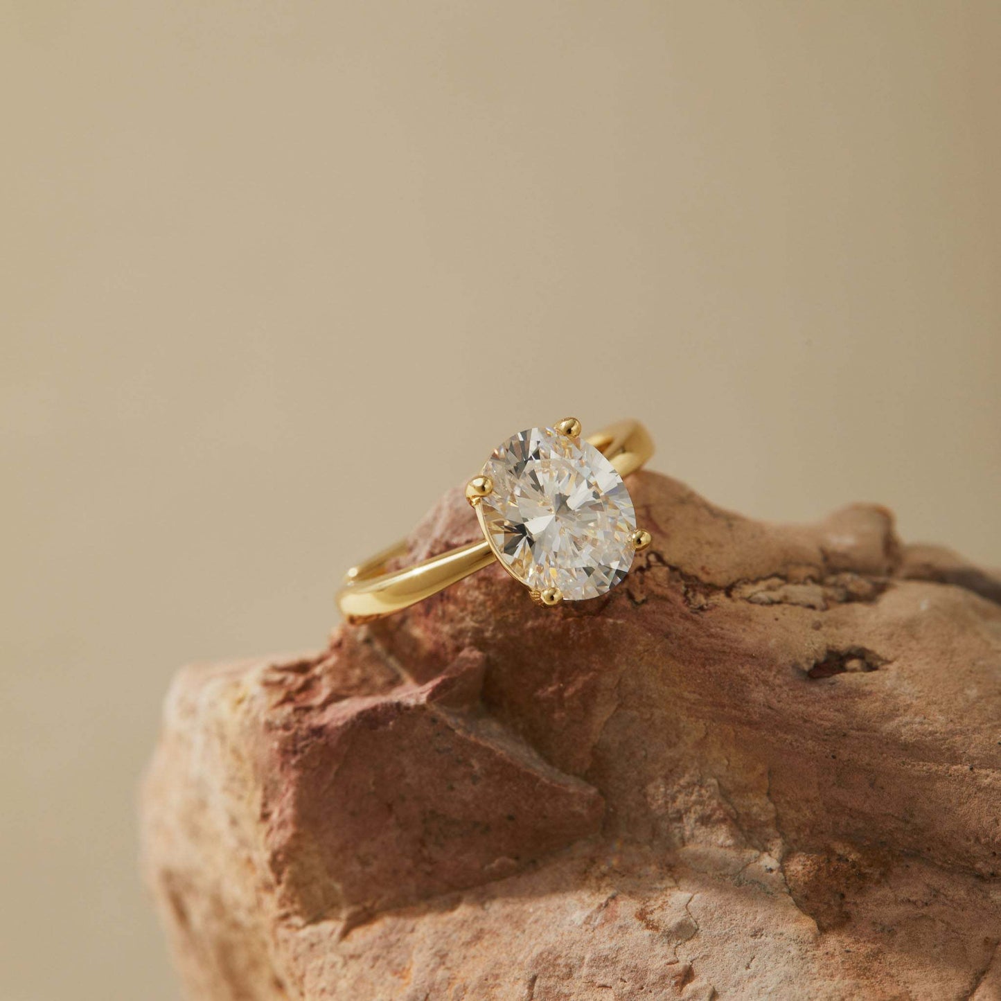 Adjustable solitaire ring in 14K gold plated S925 sterling silver resting on natural stone