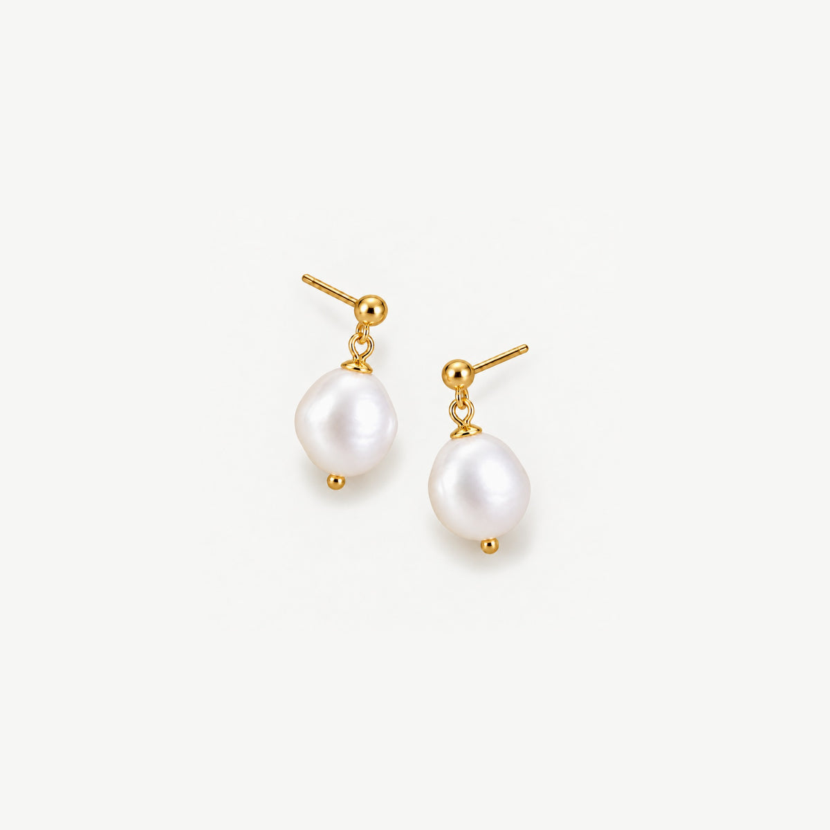 Pair of baroque freshwater pearl drop earrings on gold plated sterling silver ball studs, angled on a white background