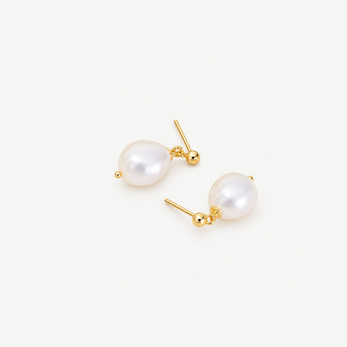 Gold plated baroque freshwater pearl drop earrings lying head to toe on a white background, posts and ball studs showing