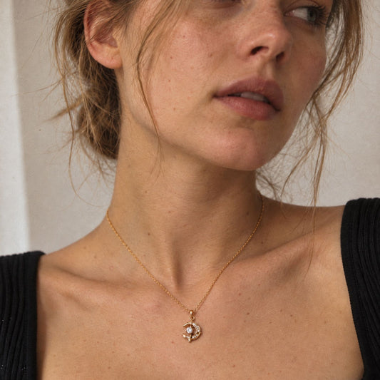Woman in a black ribbed top wearing an 18k gold-plated crescent moon dolphin necklace just below the collarbone