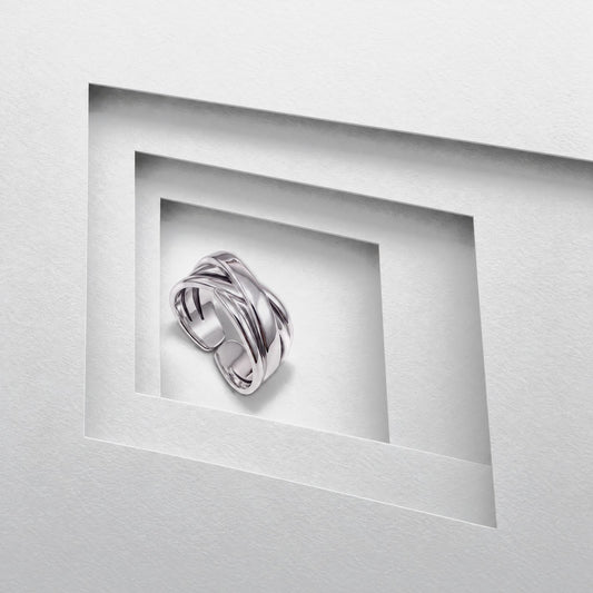 Sterling silver crossover ring standing in a stepped grey card opening, polished bands crossing over the open band
