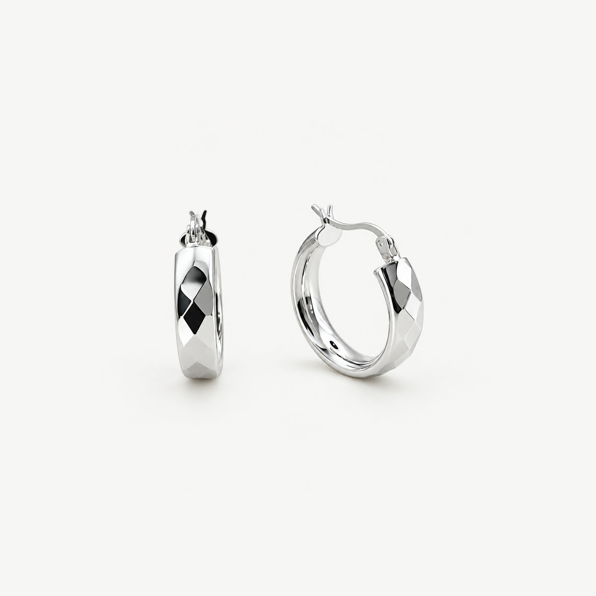 Faceted sterling silver chunky hoop earrings standing upright, one side on and one front on, hinged click tops