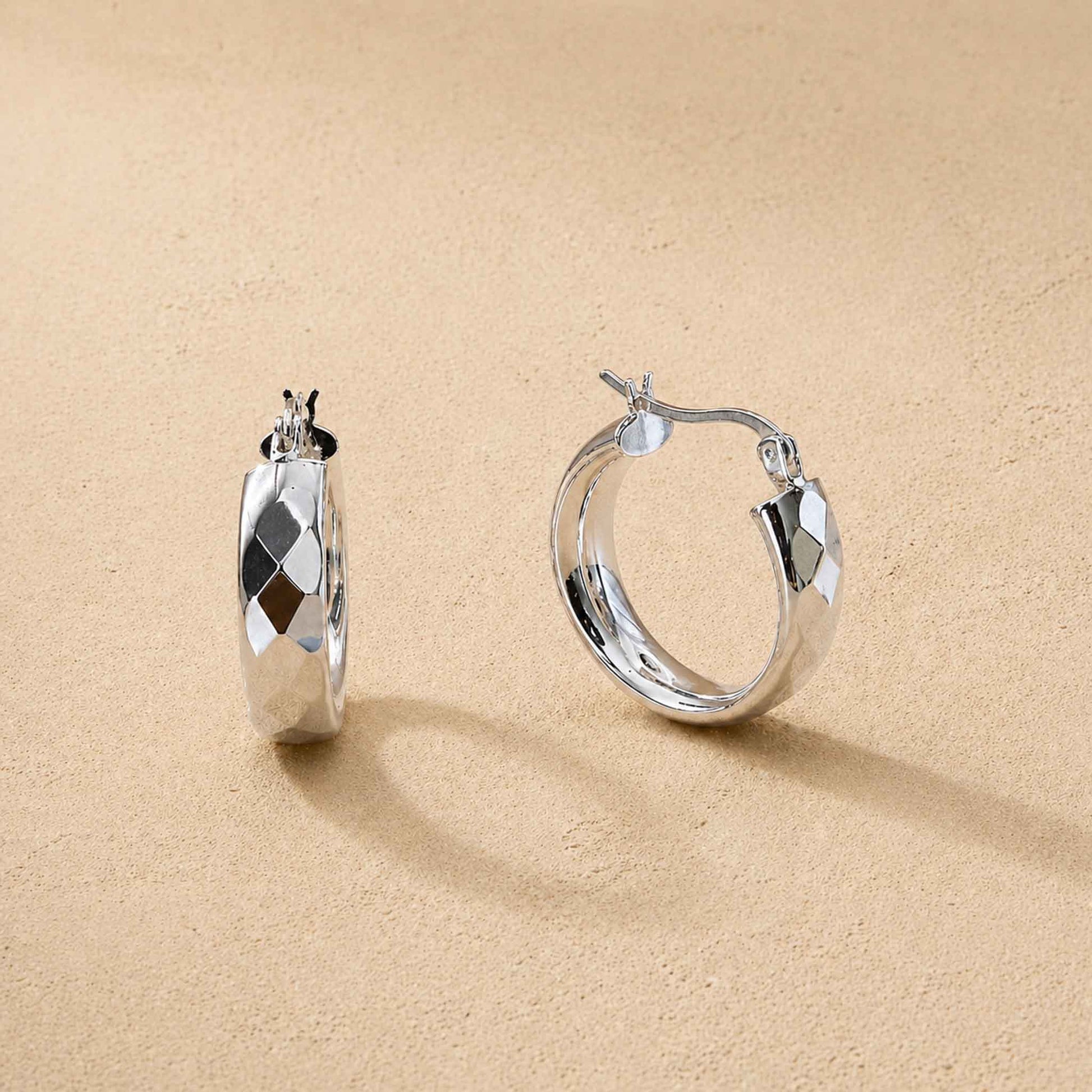 Pair of small chunky sterling silver hoop earrings with diamond-cut faceted band, front and side view