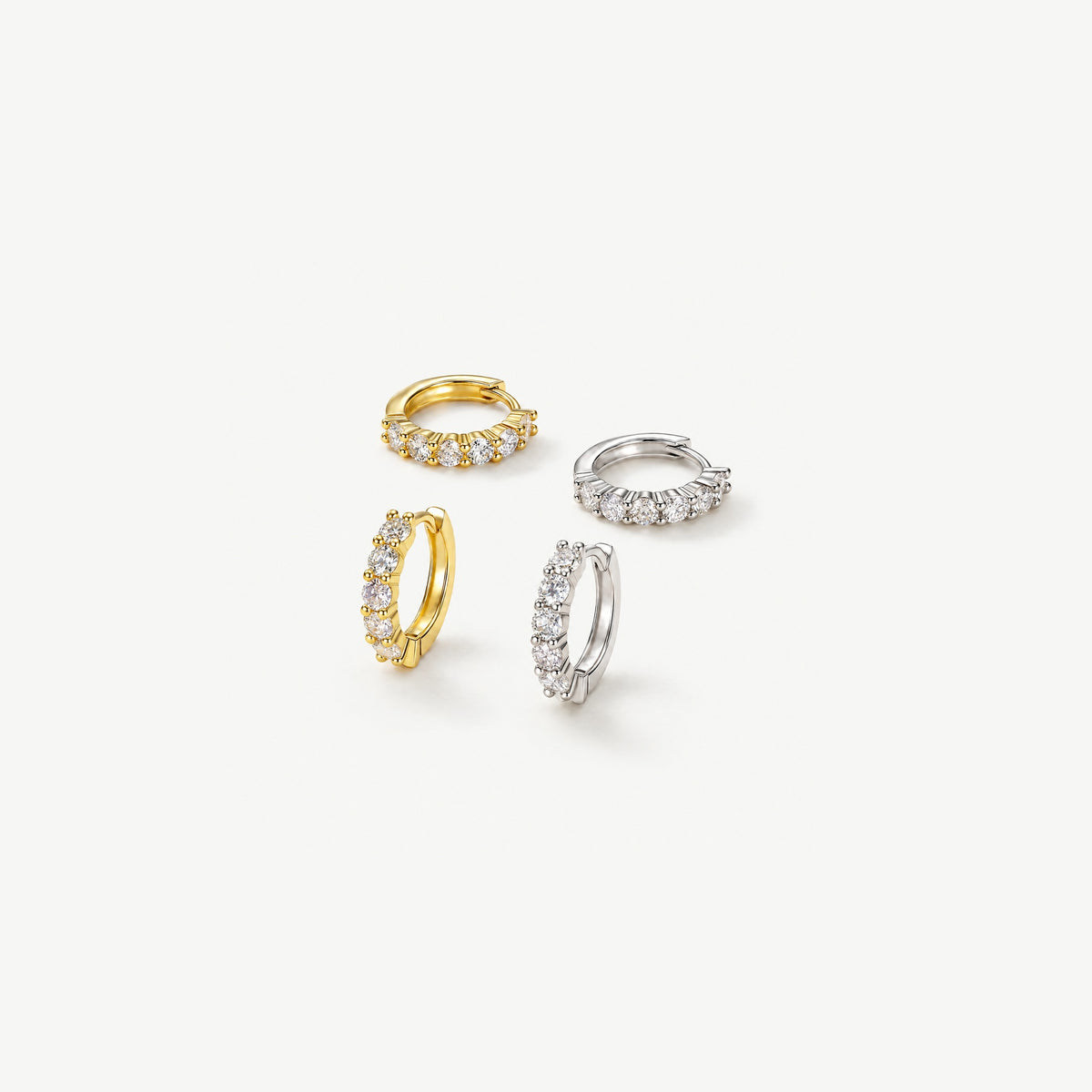 Gold plated and sterling silver moissanite huggie hoops, two pairs on off-white, two lying flat and two standing