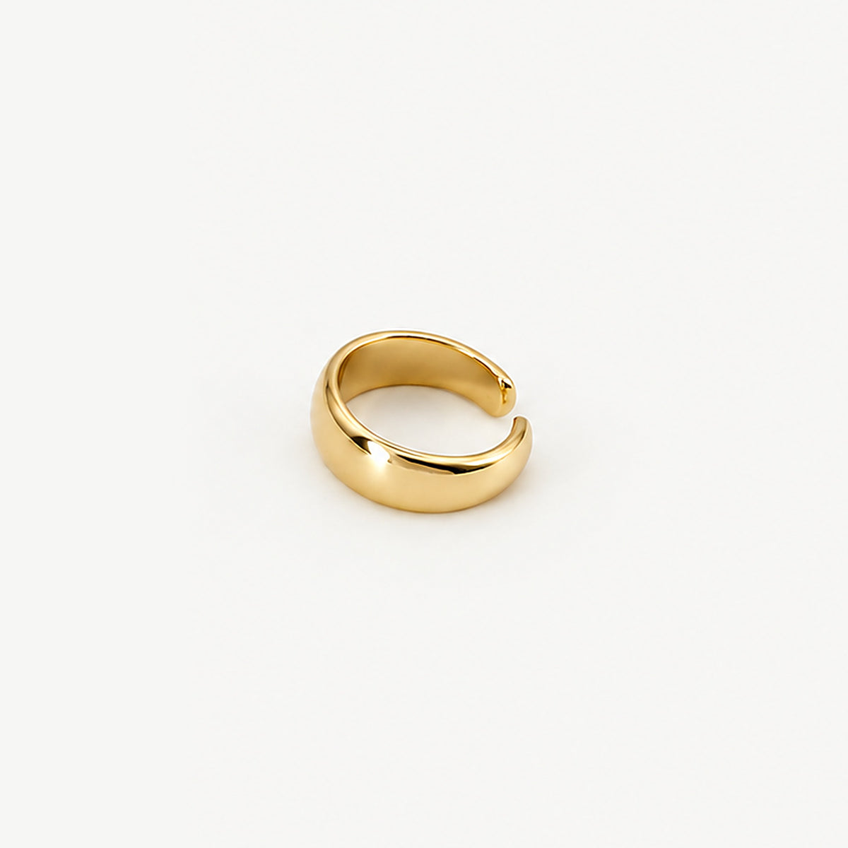 Gold-plated dome ear cuff resting on its side, the rounded band and inner surface in a high polish