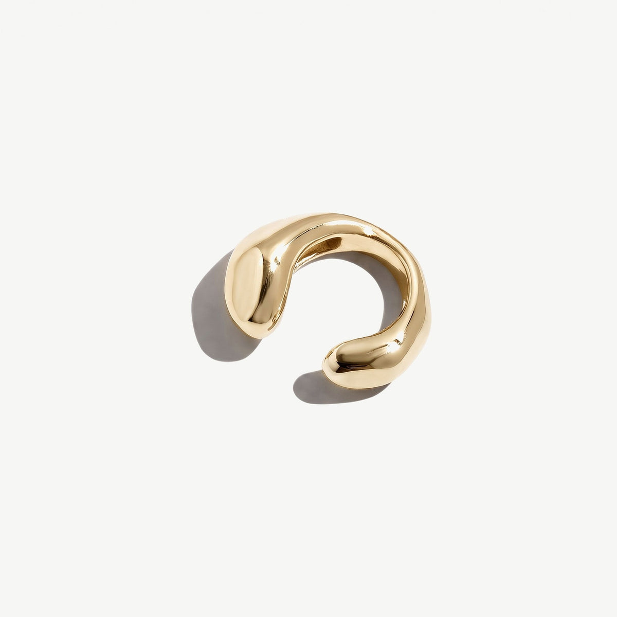 Gold plated sterling silver ear cuff resting on its side, the sculpted band seen in full width