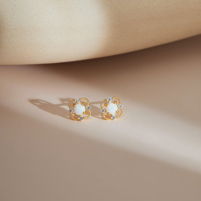 Gold S925 floral opal stud earrings resting on a soft neutral surface