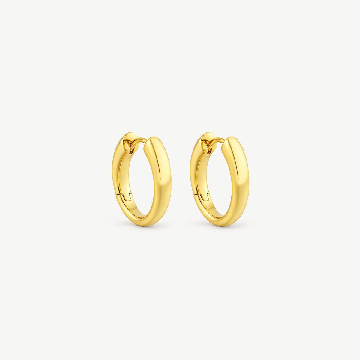 Two gold-plated huggie hoop earrings angled side by side, tapered polished bands and hinged clicker tops in view