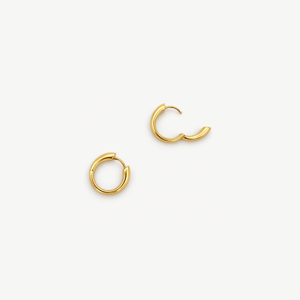 Gold-plated tapered huggie hoops from above, one closed and one open on its hinge to show the slim clicker post