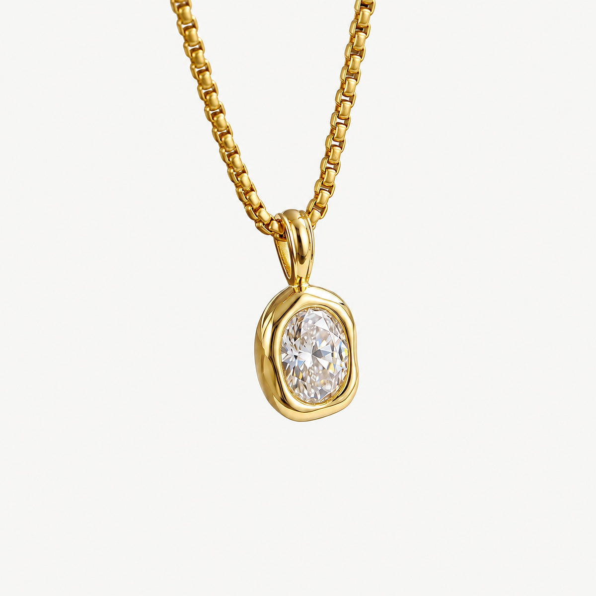 Close-up of a 14k gold plated oval pendant, an oval cubic zirconia set in an organic bezel below a rounded bail