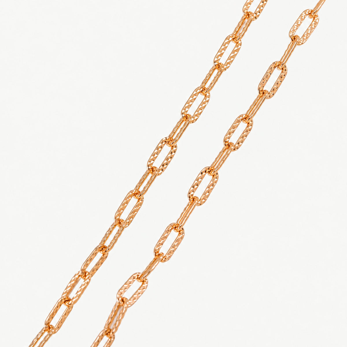 Two lengths of gold-plated paperclip chain side by side, showing the textured faceting on each short link