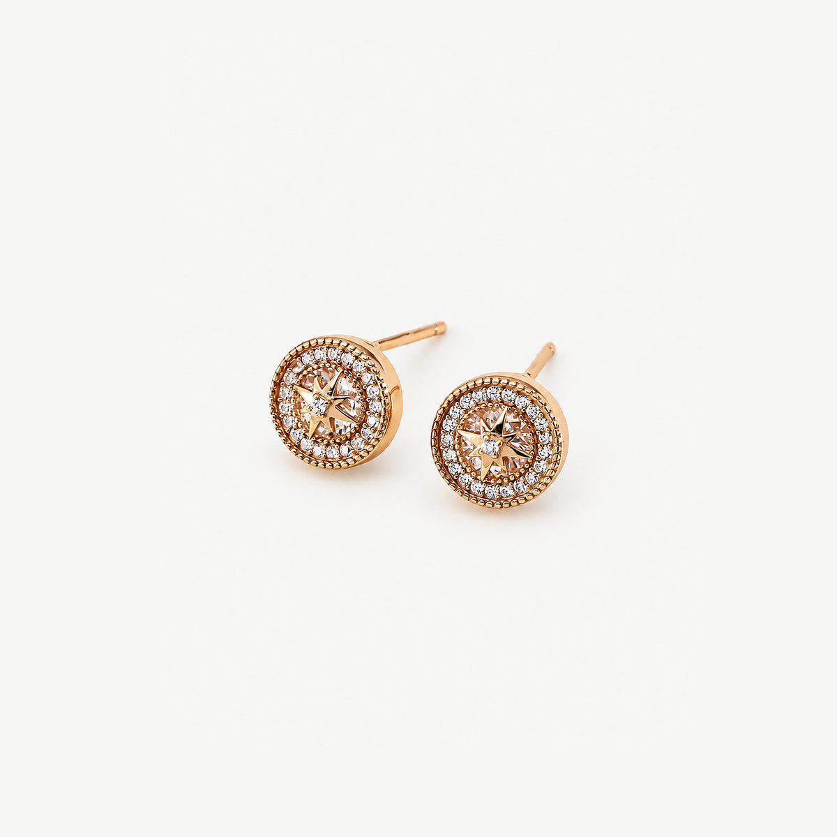 Gold-plated starburst halo stud earrings at an angle, showing the polished rim, milgrain edges and straight posts