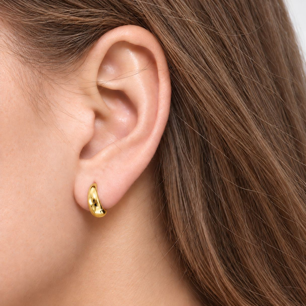 Woman with loose light-brown hair wearing an 8 mm gold-plated teardrop huggie that hugs close to her earlobe