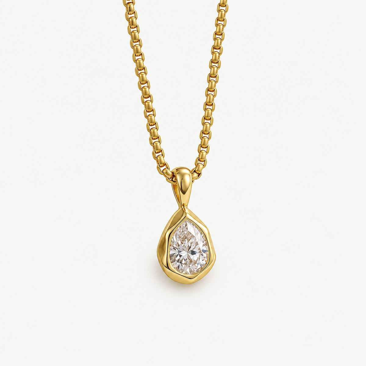 Close-up of a 14k gold plated teardrop pendant, a pear-cut cubic zirconia in an organic bezel on a box chain