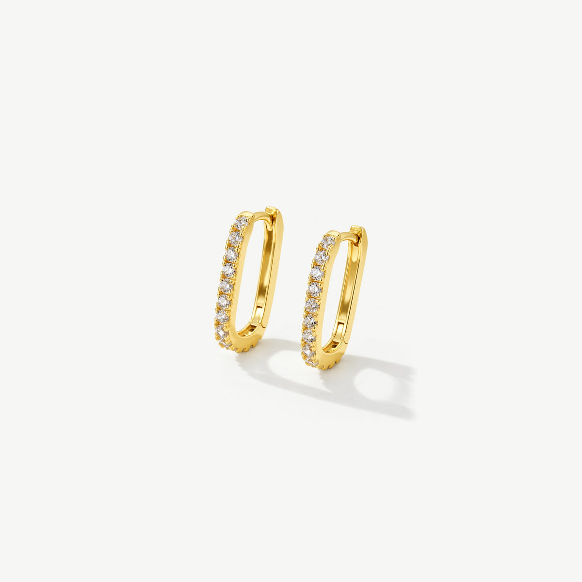 Pair of 14k gold plated U hoop huggie earrings standing at an angle, small stones set down the front of each