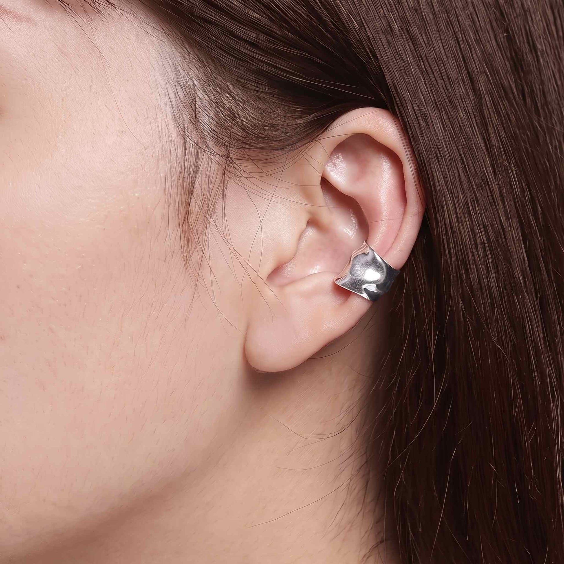 Hammered silver cuff earring on the ear rim of a brown haired model, no piercing needed