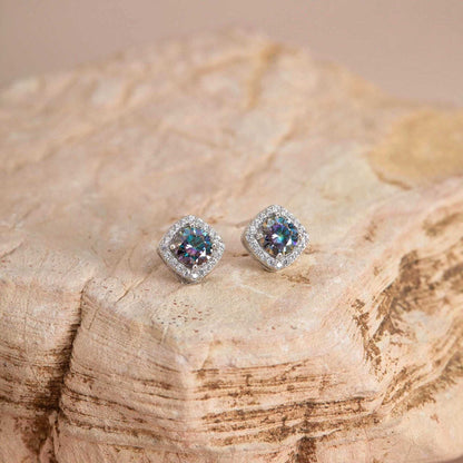 Flat lay on stone — Rainbow blue moissanite halo studs, cushion setting.