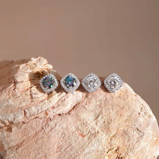 Flat lay on stone — Moissanite square halo stud earrings, sterling silver, white & rainbow blue stones.