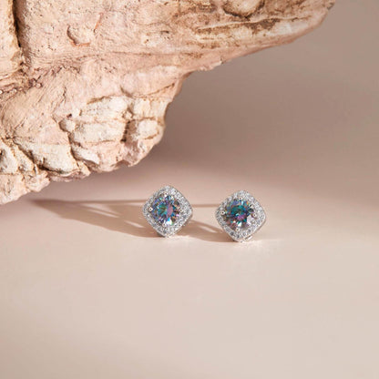 Flat lay on neutral surface — Rainbow blue moissanite halo stud earrings with sparkle.