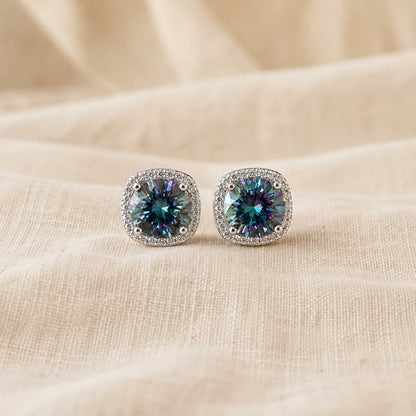 Pair of 1ct round cut rainbow blue moissanite halo stud earrings in sterling silver on cream linen