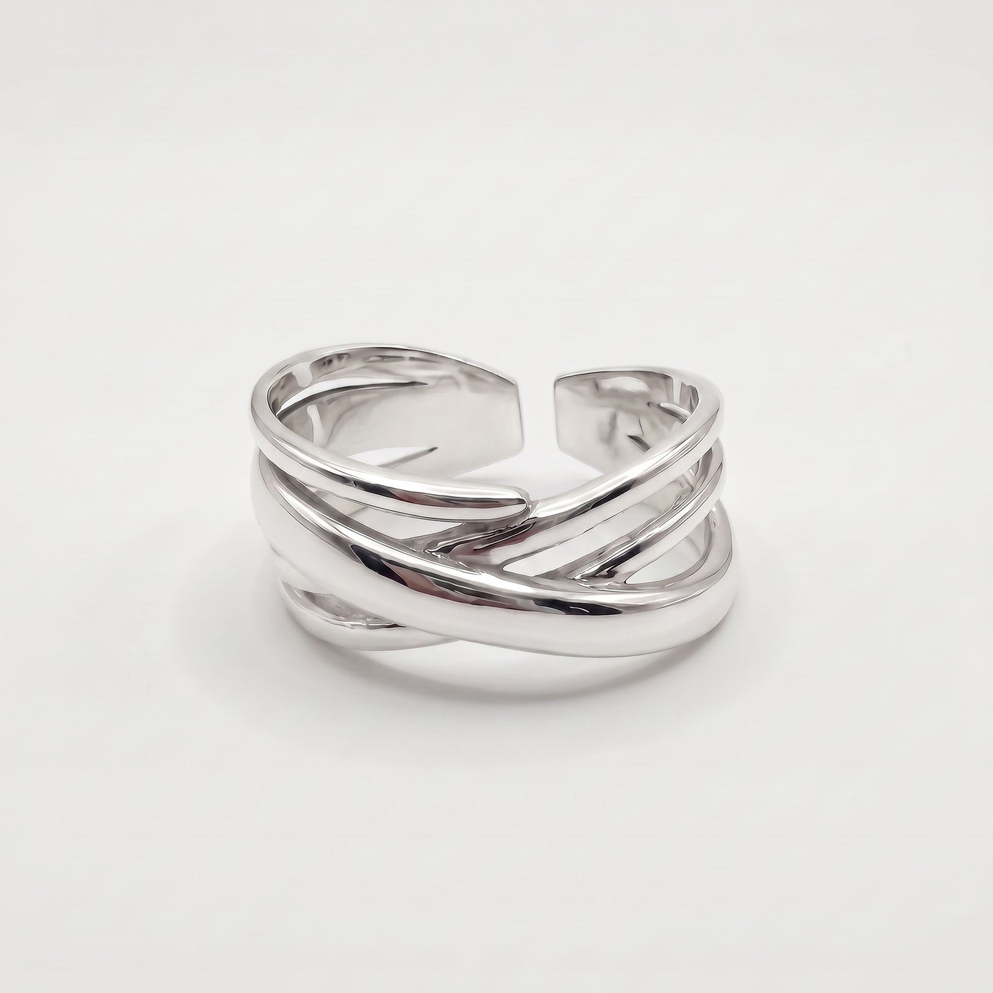 Sterling silver crossover ring with polished bands crossing over a wide open adjustable band