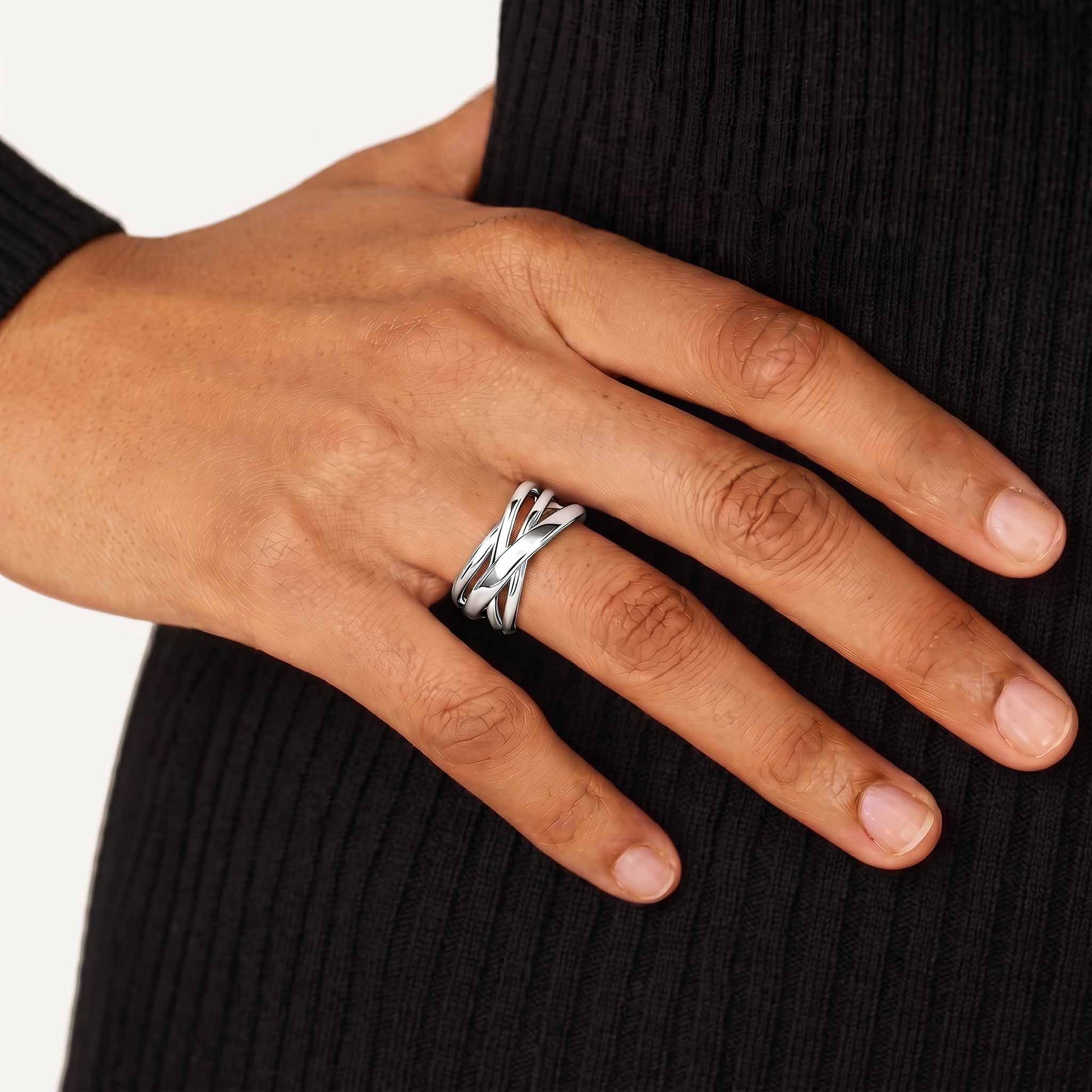 Woman wearing a sterling silver crossover ring, hand resting against a black ribbed knit dress