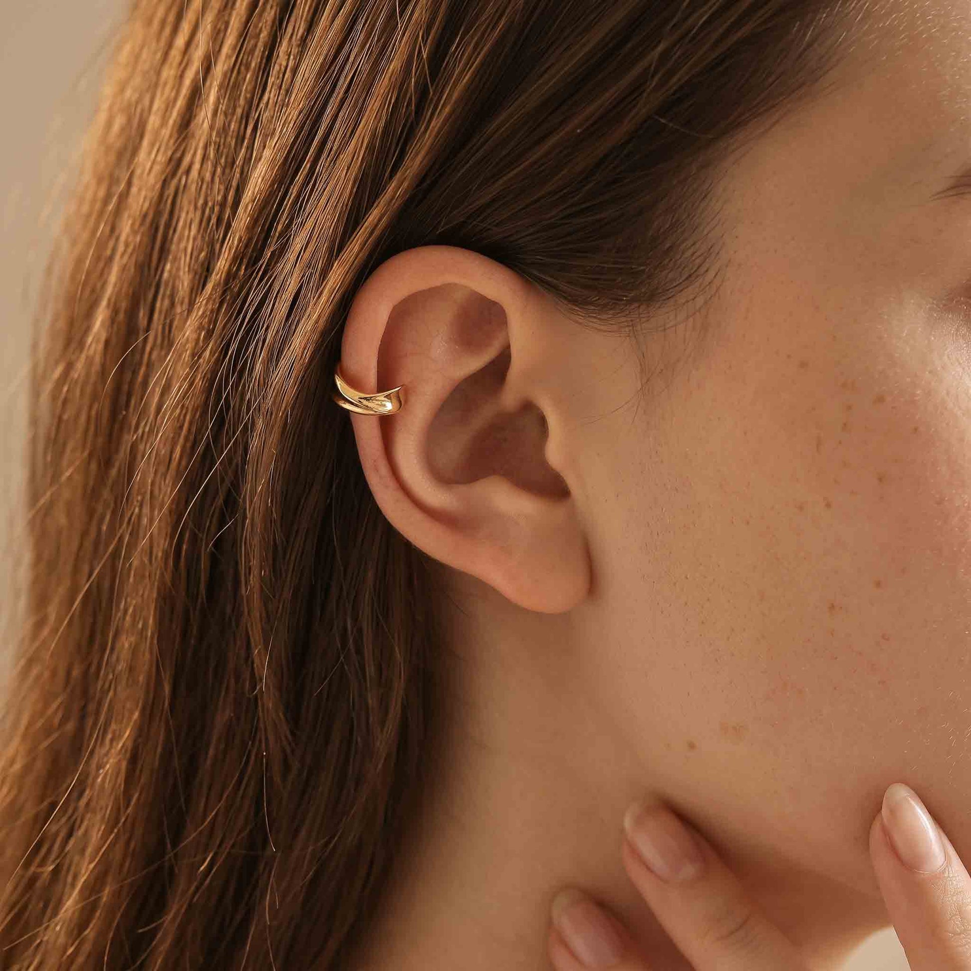 Model wearing the gold twisted ear cuff high on the upper ear rim, worn without a piercing