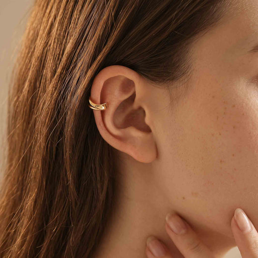 Model wearing the gold twisted ear cuff high on the upper ear rim, worn without a piercing