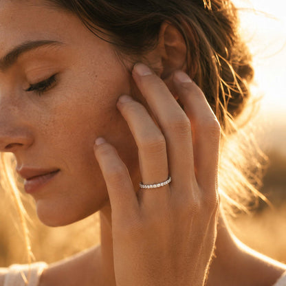 Sterling silver moissanite pavé eternity ring worn on model finger in warm golden hour sunlight