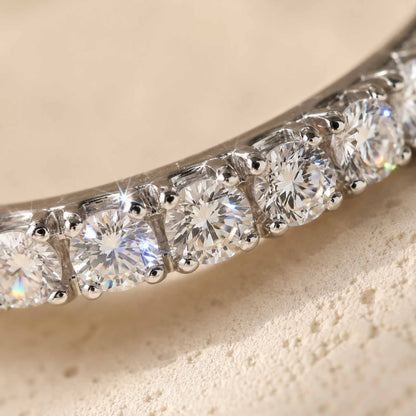 Macro detail of pavé-set moissanite stones on sterling silver eternity ring, showing prong setting
