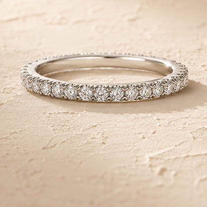 Sterling silver moissanite eternity ring with 31 pavé-set stones, top view on cream textured surface