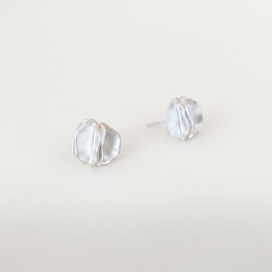 Pair of sterling silver statement stud earrings with folded petal detail on a plain near-white background