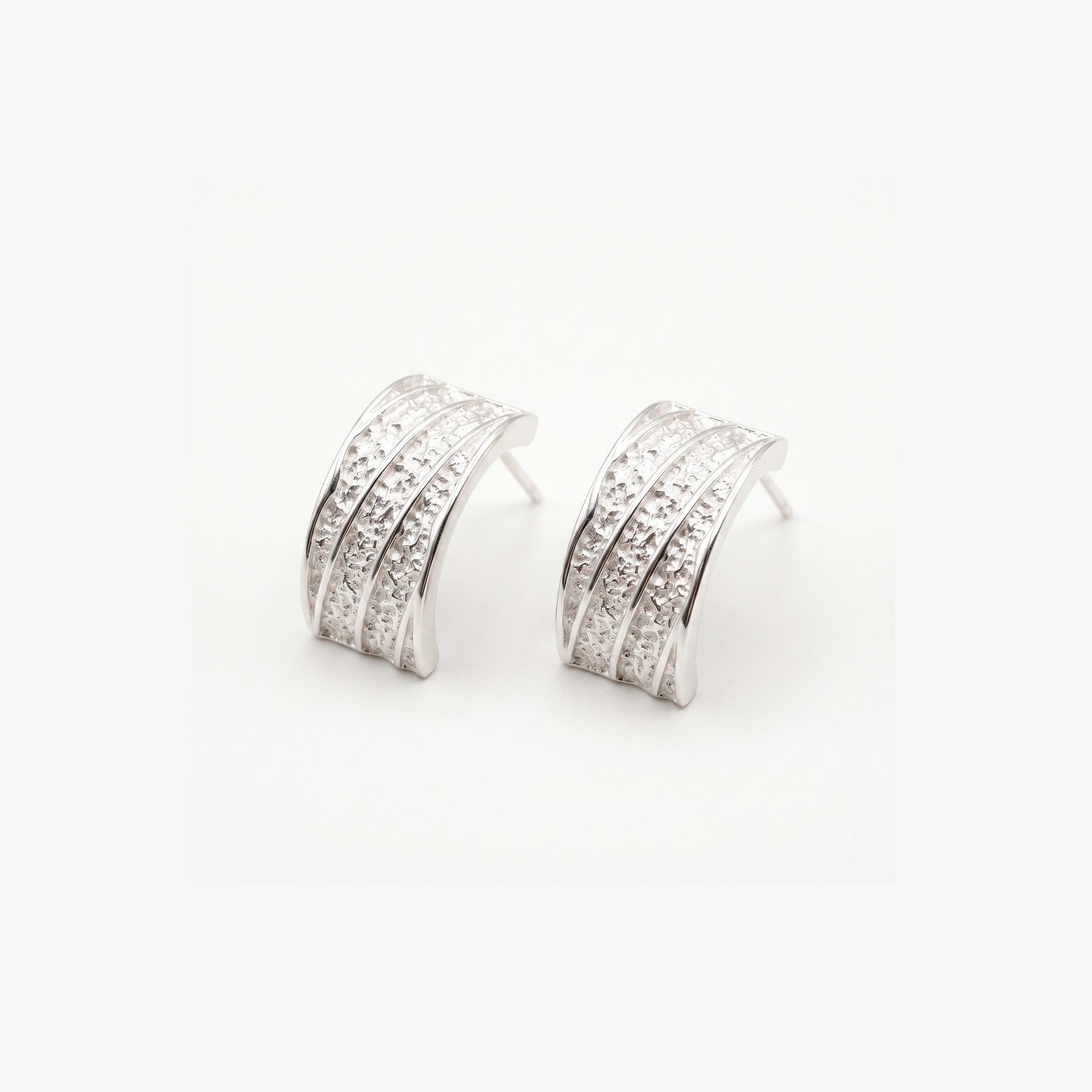 Pair of chunky sterling silver hammered half hoop earrings with polished ribs, shown on a plain white background