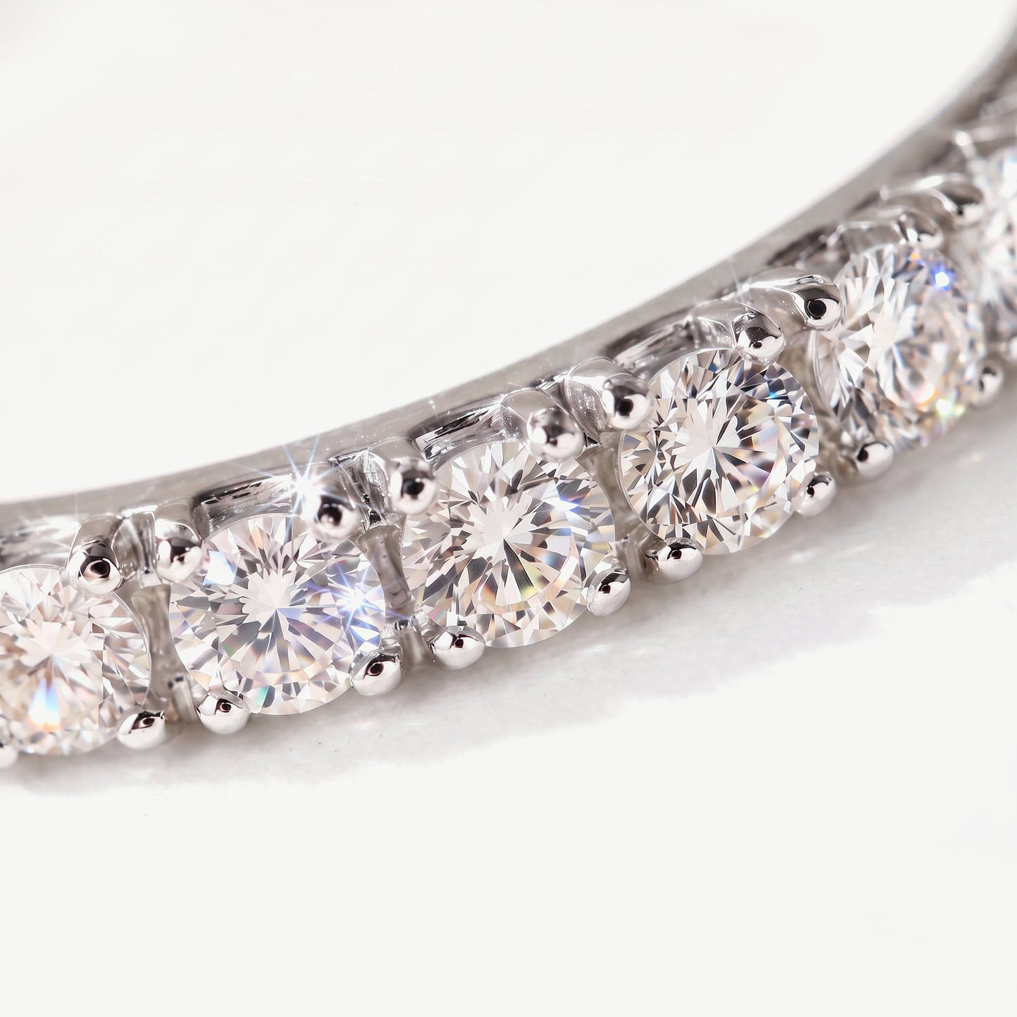 Macro of claw set round moissanite stones on a sterling silver eternity ring, showing the prong setting