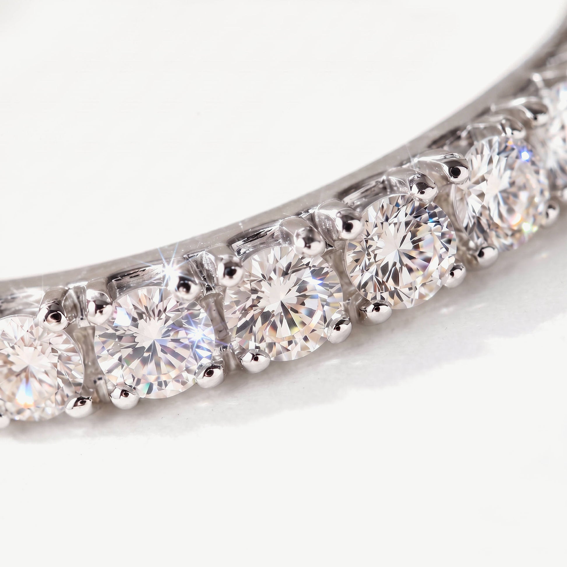 Macro of claw set round moissanite stones on a sterling silver eternity ring, showing the prong setting