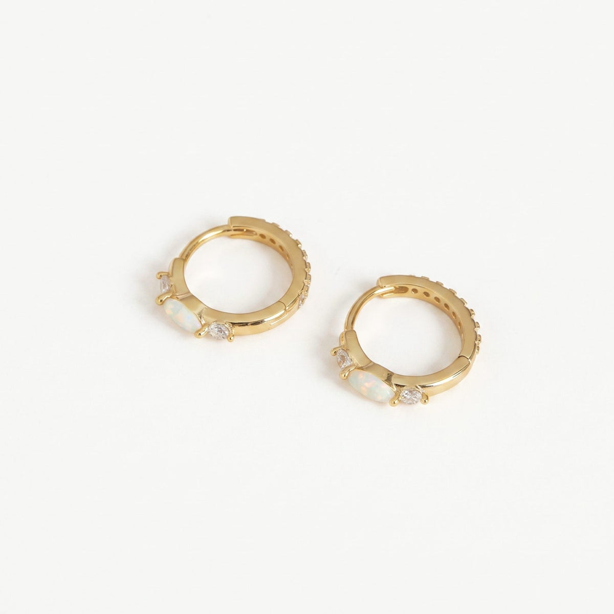 Gold plated opal huggie hoop earrings with marquise opal and cubic zirconia accents on a plain near-white background