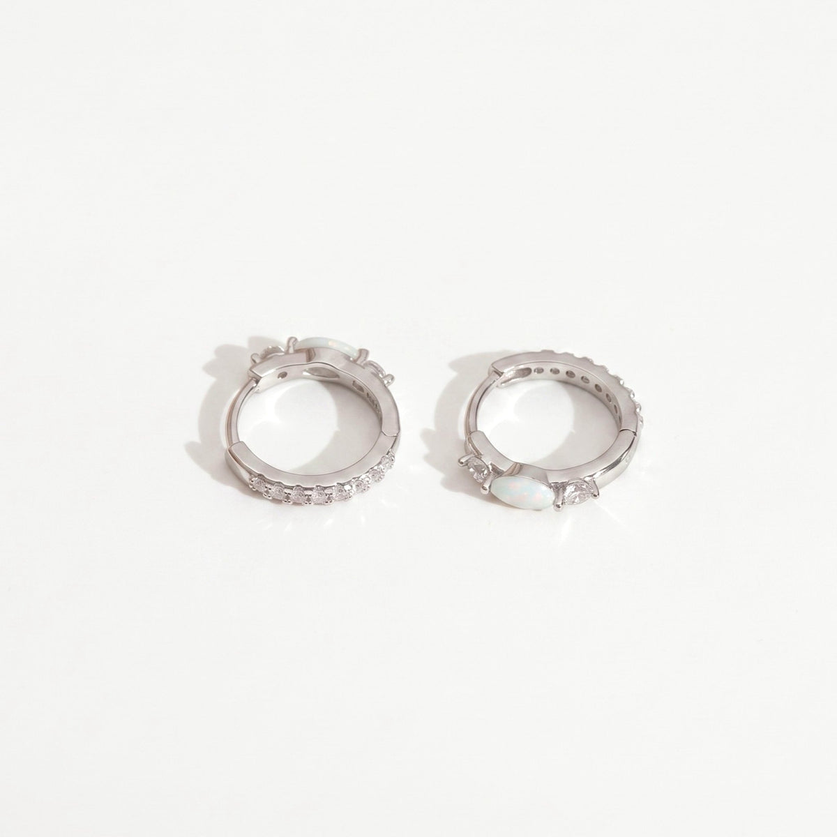 White gold opal huggie hoop earrings with marquise opal and cubic zirconia accents on a plain near-white background