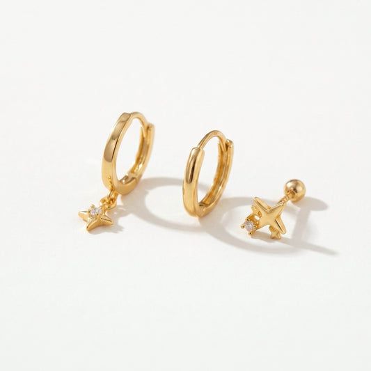 Gold plated star huggie earring set of three on a plain near-white background, two hoops and a star stud