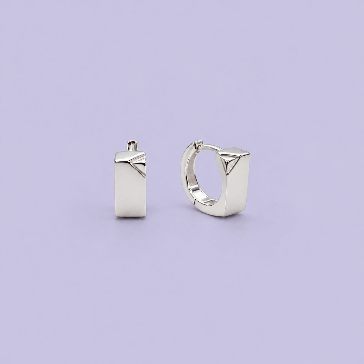 Pair of small sterling silver rectangle huggie earrings on a pale lavender backdrop, front and side view