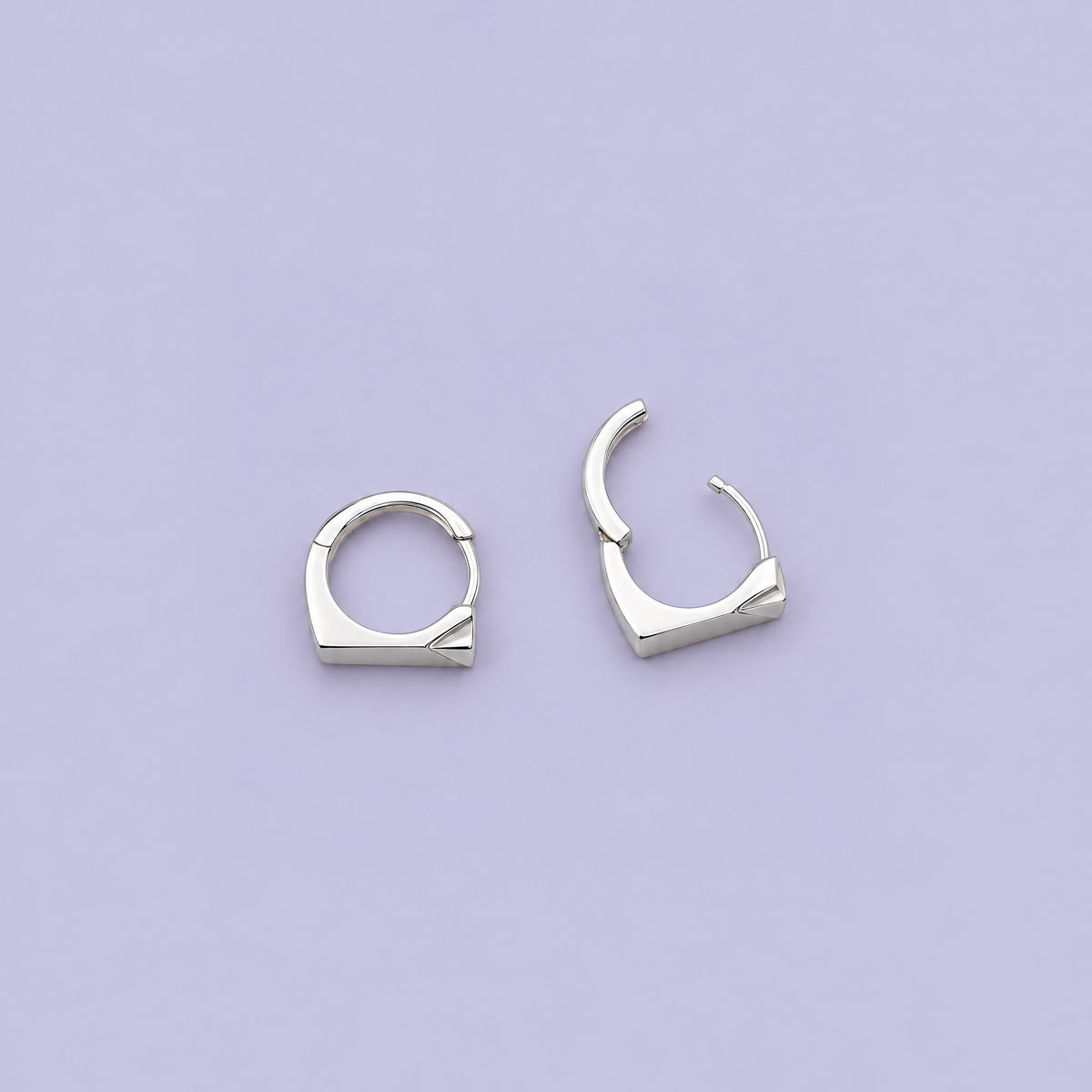 Sterling silver rectangle huggie earrings from above on pale lavender, one open on its hinge to show the clicker