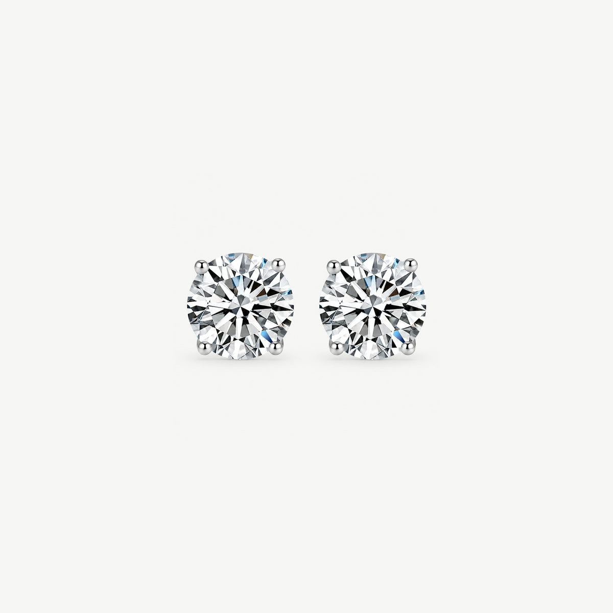 Pair of round moissanite solitaire stud earrings in sterling silver, face on and close, four prongs on each stone