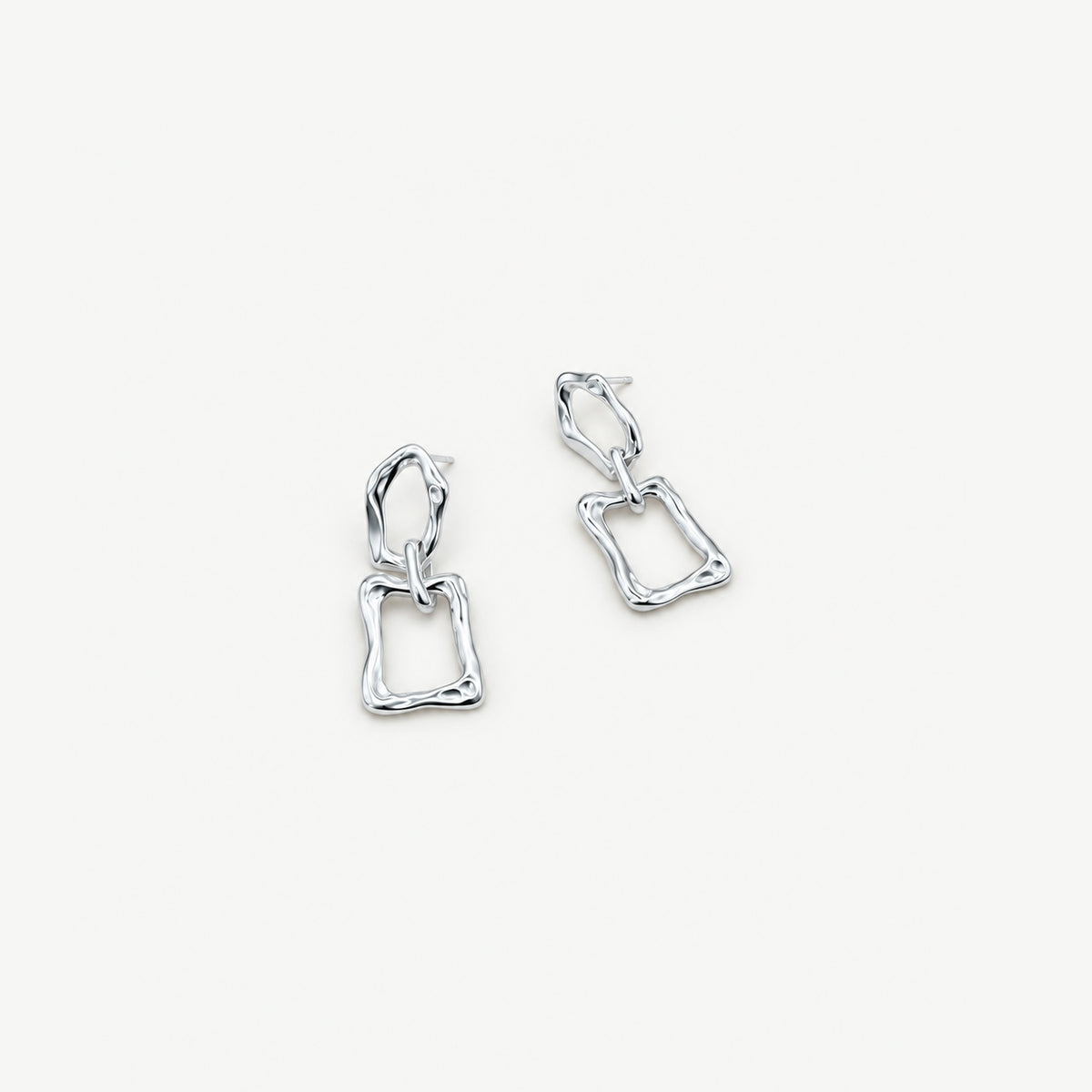 Two sculptural sterling silver dangle earrings lying flat at an angle, posts and both linked frames seen from above