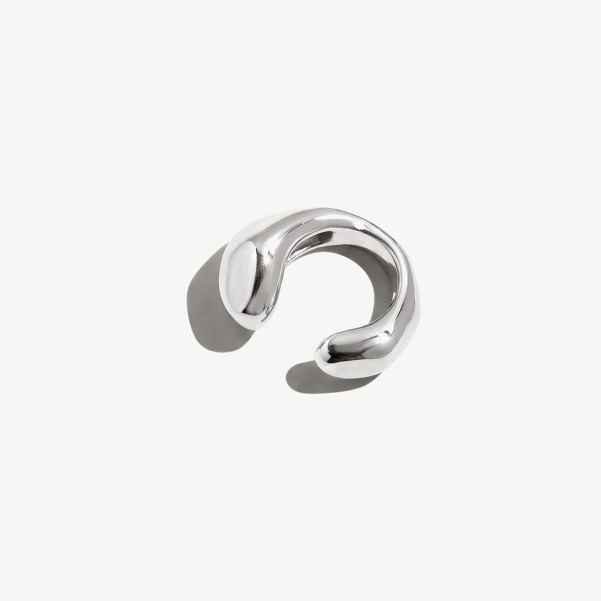 Sterling silver ear cuff resting on its side, showing the full width of the sculpted open band