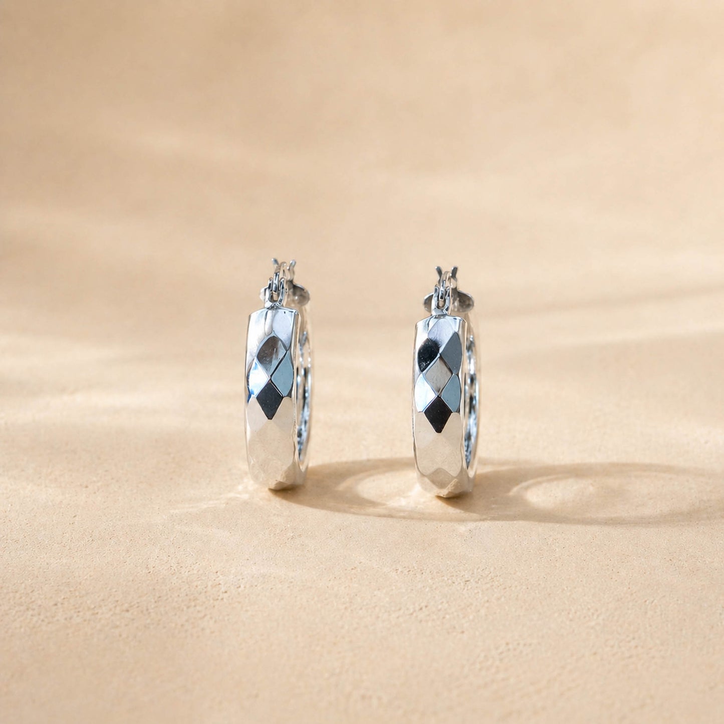 Close-up of multi-faceted polished surface on sterling silver hoop earrings, diamond-cut detail