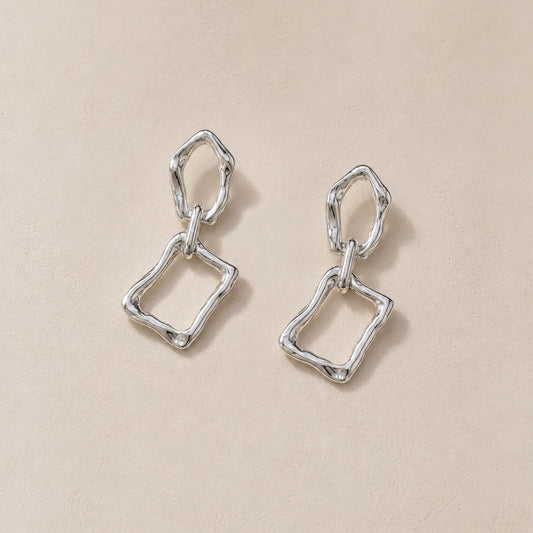 Close-up of sterling silver dangle earrings showing molten pebble top and irregular rectangular frame below