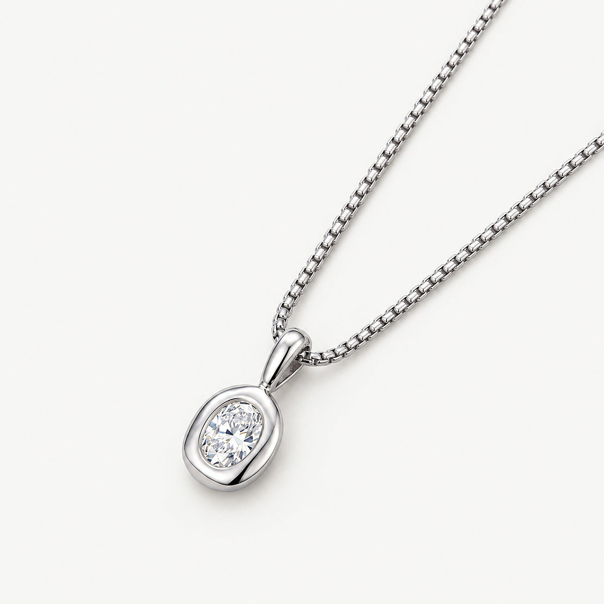Silver tone stainless steel oval pendant necklace on a box chain, the bezel-set oval stone seen at an angle