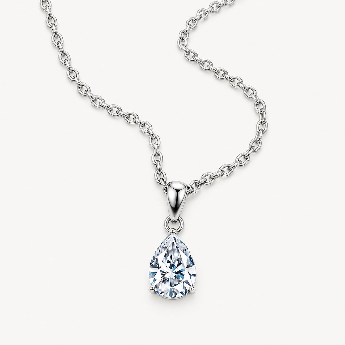 Silver tone stainless steel pear solitaire necklace with the cable chain curving across a pale ground